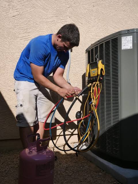 Technician using service gauges to inspect a residential outdoor HVAC system