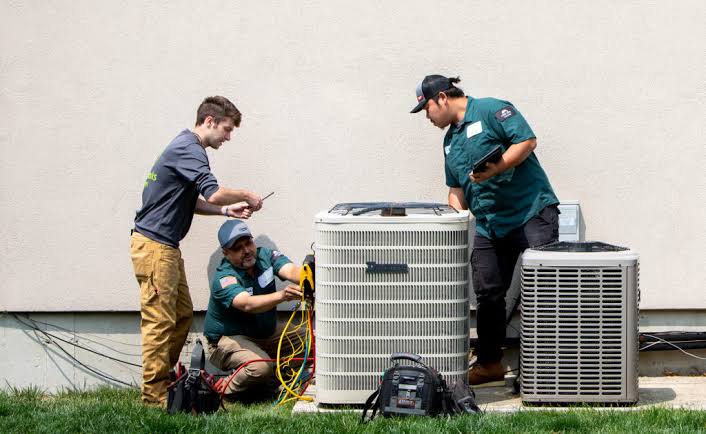 HVAC technicians inspecting outdoor condensers and checking system performance