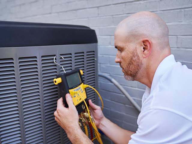Technician using a digital diagnostic instrument beside an outdoor HVAC unit