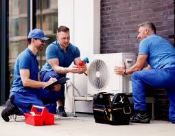 Three HVAC technicians reviewing a compact outdoor air conditioning system