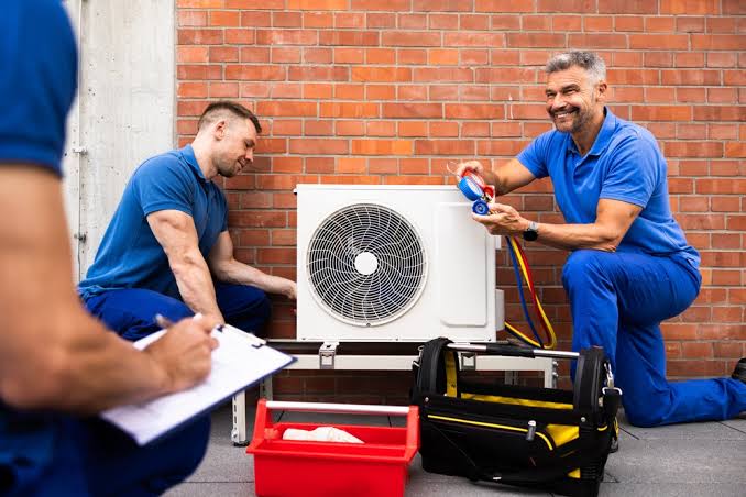 HVAC service team inspecting an outdoor unit and discussing diagnostic readings